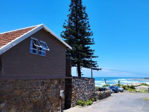 马盖特Billy Bay Cottage的一座石墙、一棵树和大海的房子