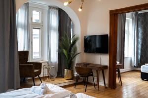 Schlafzimmer mit einem Bett und einem Schreibtisch mit einem TV in der Unterkunft JUNIK Apartments - Deine Cityapartments in Duisburg in Duisburg