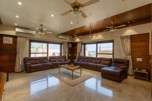 a living room with brown leather couches and a table at The Gaj Kesri Gir - Best Wildlife Resort in Gir in Dudhāla