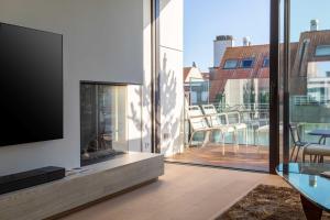 a living room with a television and a balcony at Stunning duplex - 3 bedroom - 2 sunny terrasses in Knokke-Heist