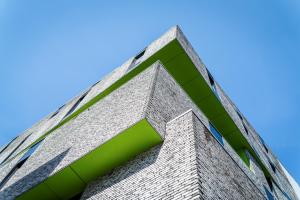 een hoog bakstenen gebouw met groene ramen bij De Ploate Hostel in Oostende