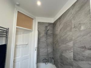 a bathroom with a shower and a white door at 4 bed house 10 min walk to Tube in London