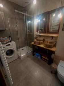 a bathroom with a shower and two sinks and a washing machine at Apartament Trawertynowy Chrobrego 15 Sopot in Sopot