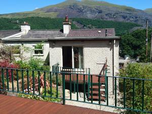 a small white house with a balcony with a mountain at Llety'r Wyddfa in Caernarfon