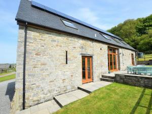 a stone building with a patio and a table at 4 Bed in Kidwelly CWRTY in Kidwelly