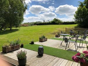 a deck with a table and chairs and a field at Offa's Dyke Lodge B&B in Gladestry