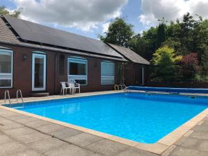 a swimming pool in front of a house with a solar roof at Offa's Dyke Lodge B&B in Gladestry