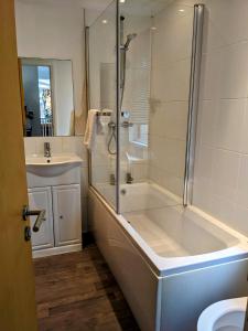 a bathroom with a shower and a tub and a sink at Puddleduck Lodge with Hot Tub on Felmoor Park in Morpeth