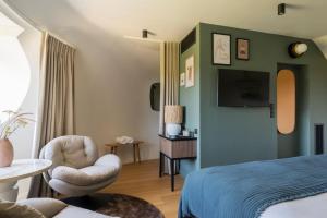 - une chambre avec un lit, une chaise et une télévision dans l'établissement L'EssenCiel, à Piré-sur-Seiche