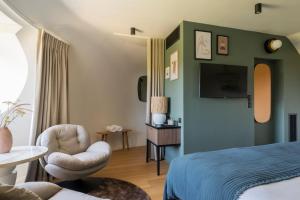 a bedroom with a bed and a chair and a tv at L'EssenCiel in Piré-sur-Seiche