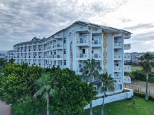 a large white building with palm trees in front of it at Aydinbey Gold Dreams in Avsallar