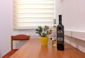 a bottle of wine sitting on a table with a plant at Apartmani Sebastijan in Banja Luka +16 photos