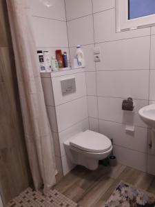 a white bathroom with a toilet and a sink at Całoroczny Apartament u Grzegorza in Lidzbark