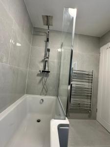 a bathroom with a bath tub and a shower at Harrys Home - Weekly & Monthly Offers - Near NEC - Contractors & Business professionals - 2 Parking spaces - 4 Large Bedrooms & 2 Bathrooms - Pool - Table Tennis - Darts - Games console in Wyken