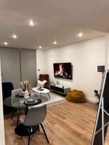 een woonkamer met een tafel en een tv aan de muur bij Home away from home in Birmingham