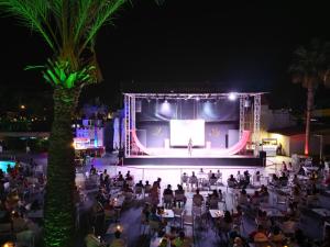 een menigte mensen die 's nachts op een podium zitten bij Aydinbey Famous Resort in Belek