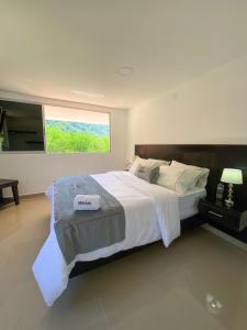 1 dormitorio con 1 cama grande y ventana grande en Malokas Resort - Socorro - San Gil, en Socorro