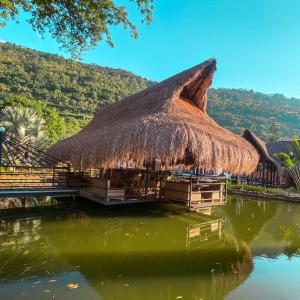 a hut with a thatched roof in the water at Malokas Resort - Socorro - San Gil in Socorro