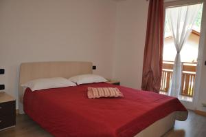 ein Schlafzimmer mit einem Bett mit einer roten Decke darauf in der Unterkunft Appartamento Angeli in Croviana