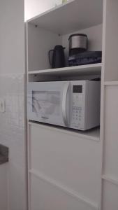 a white microwave in a white shelf in a kitchen at Loft lindo, acochegante e reservado in Boa Vista