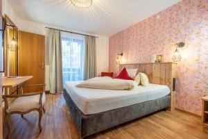 a bedroom with a bed and a table and a desk at Hotel Krone Tirol in Reutte