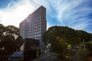 Un edificio alto con un árbol delante. en San Diego Express Barro Preto, en Belo Horizonte