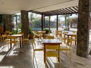 um restaurante com mesas de madeira e cadeiras amarelas em Búzios Beach Resort em Búzios