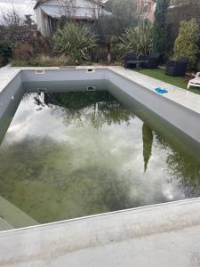 uma piscina com um reflexo do céu na água em Maison T 1 meublé confort proche aéroport em Pusignan