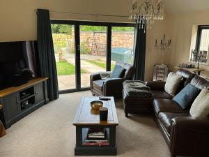 a living room with a couch and a table at Barn conversion with hot tub in Lincoln