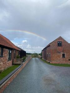 a road between two brick buildings with a rainbow in the sky at Barn conversion with hot tub in Lincoln