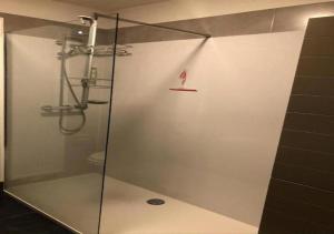 um chuveiro com uma porta de vidro na casa de banho em B&B Villa Verde em De Haan