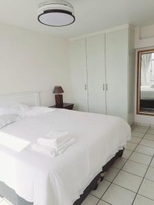 a bedroom with a white bed with towels on it at Cosy apartment by the sea in Durban
