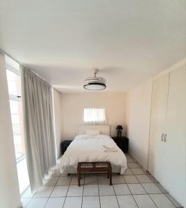 a white bedroom with a bed and a window at Cosy apartment by the sea in Durban