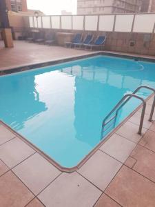 a large swimming pool with blue water and stairs in it at Cosy apartment by the sea in Durban