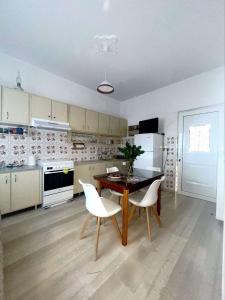 a kitchen with a wooden table and white chairs at Pet friendly House in Tríkala