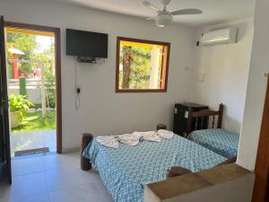sypialnia z łóżkiem, telewizorem i oknem w obiekcie POUSADA SOL DE VERÃO - Cumuruxatiba -BA w mieście Prado