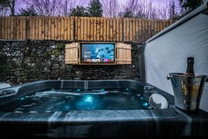 Stunning cottage Grade 2 listed with parking and Hot Tub في باونيس أون وينديرمير: حوض جاكوزي مع تلفزيون على الحائط