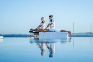 a group of people sitting on the edge of a swimming pool at DeLight Boutique Hotel - Small Luxury Hotels of the World in Agios Ioannis Mykonos