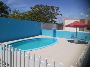 a blue swimming pool with a fence and an umbrella at Casa para temporada! Valores especiais para médias e longas estadias in Aracaju