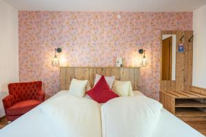 Schlafzimmer mit einem Bett mit weißer Bettwäsche und roten Kissen in der Unterkunft Hotel Krone Tirol in Reutte