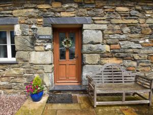 a wooden door and a bench in front of a stone building at 2 Bed in Fairbourne 43105 in Arthog