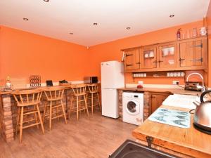 a kitchen with orange walls and a white refrigerator at 4 Bed in Whaley Bridge PK535 in Whaley Bridge