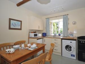 a kitchen with a wooden table with chairs and a dining room at 1 Bed in Bourton-on-the-Water 44961 in Withington