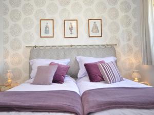 a bedroom with two beds with purple and white pillows at 1 Bed in Bourton-on-the-Water 44961 in Withington