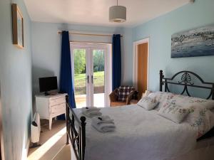 um quarto com uma cama e uma porta de vidro deslizante em Offa's Dyke Lodge B&B em Gladestry