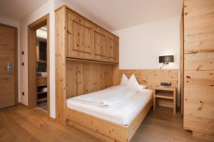 a bedroom with a bed with a wooden wall at Hotel Bergblick in Fiss