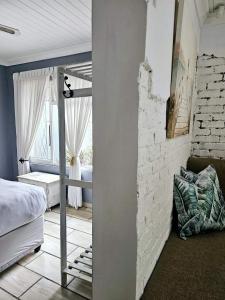 een slaapkamer met een bed en een bakstenen muur bij le'Cottage on Raymond in Scottburgh