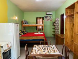 Habitación pequeña con mesa, cama y nevera. en Barra Quintal - Studio 1, en Barra Grande