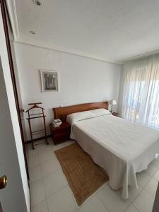 a bedroom with a large white bed and a window at Apartamento en Benicassim. in Benicàssim