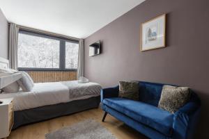 - une chambre avec un lit et un canapé bleu dans l'établissement Beautiful mountain view studio by the lake, à Chamonix-Mont-Blanc